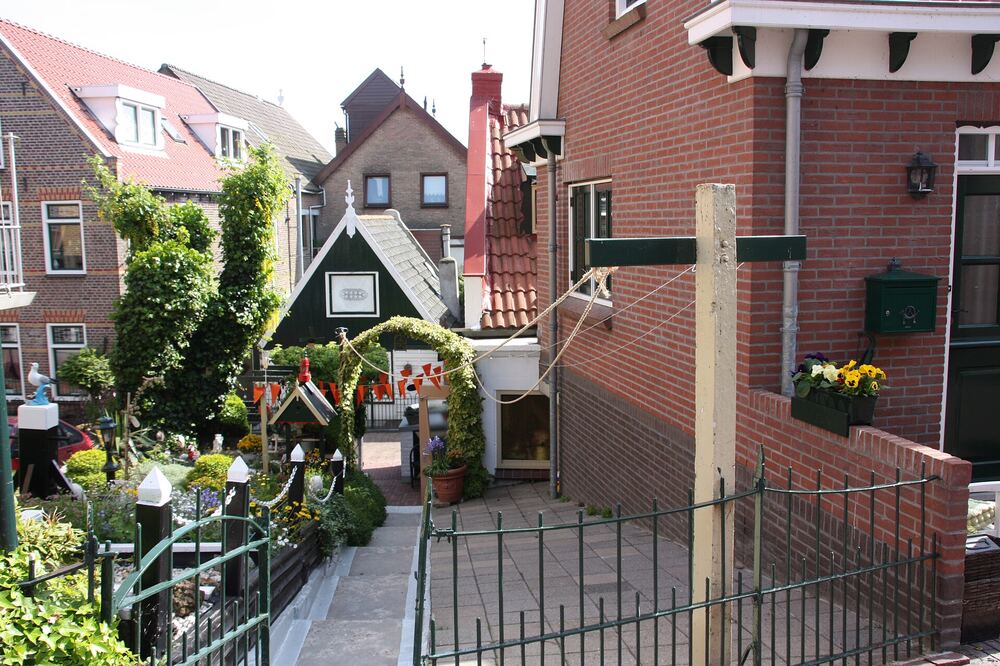 Smal steegje met trapjes en bloeiende voortuintjes tussen de oude huizen van Urk, met vlaggetjes gespannen over het pad